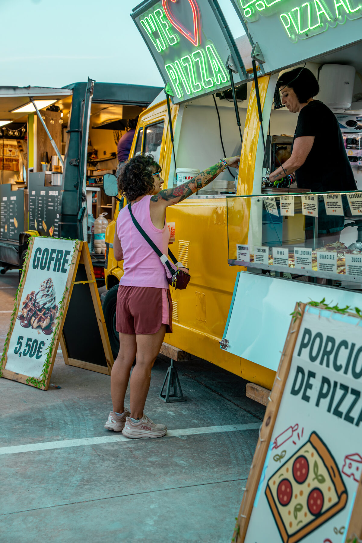 Clienta pidiendo pizza al corte en la ventanilla del food truck Altaglio