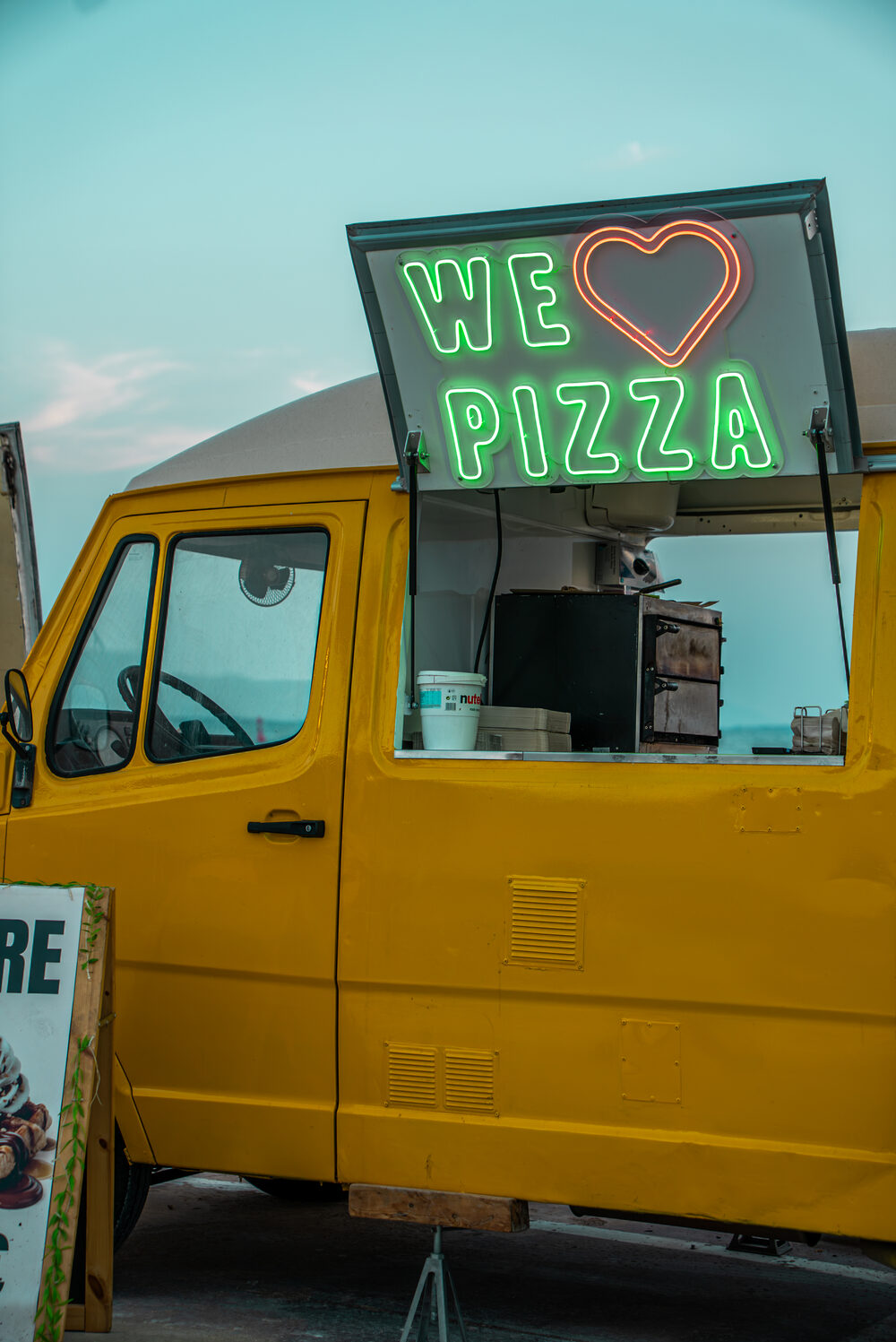 Cartel de neón We Love Pizza en el food truck Altaglio